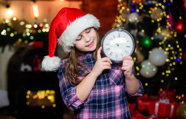 Are you ready. Time to celebrate. Happy new year. Elf child with clock. Xmas tree. Happy holiday. Little girl in red hat. Happy christmas. Santa claus little girl. Christmas interior. Christmas time
