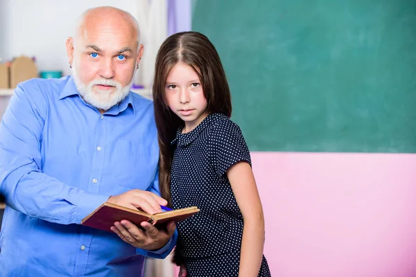 Verso la conoscenza. insegnante maturo aiutare allievo con la letteratura. piccola ragazza con libro di studio tutor uomo. informazioni. Concetto di libreria. lezione di lettura scolastica. Ricevuto. Torniamo a scuola. Leggi e scrivi — Foto Stock