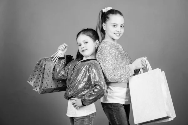 Feliz día de los niños. Hermanitas de compras en línea. Ventas y descuentos. Hermandad y familia. ahorros en compras. Moda infantil. asistente de tienda con paquete. Chicas pequeñas con bolsas de compras —  Fotos de Stock