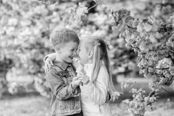 Tender love feelings. Couple kids on flowers of sakura tree background. Little girl enjoy spring flowers. Giving all flowers to her. Surprising her. Kids enjoying pink cherry blossom. Romantic babies — Stock Photo, Image