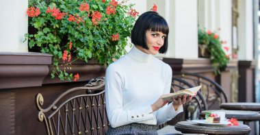 İş kadını kahve molasında kitap okurdu. Mükemmel hafta sonu için kahve ve iyi bir kitap. Kişisel gelişim konsepti. Kadınlar kafeterya terası okumaktan zevk alır. Modern kadın edebiyatı