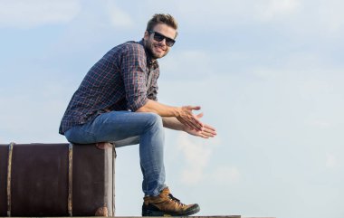 Macera zahmete değer. Gezgin, uçuşu bekle. Çekil şuradan. Seksi erkek gökyüzü arka planı. Maço, tıraşsız bir adam tur çantasına oturur. Erkek modası. Çok modaya uygun görünüyorsun. Gözlüklü iş adamı. iş gezisi