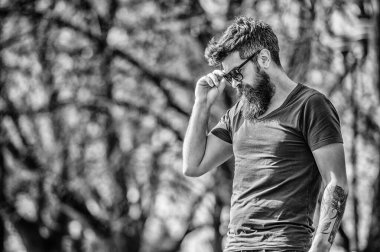 UV filtresi. Sakallı hippi vahşi adam koruyucu güneş gözlüğü takıyor. Güneş gözlüklü, sakallı, doğa geçmişi olan bir adam. Hippi koyu güneş gözlüklerine güveniyor. Sakallı adam modern güneş gözlüğü takıyor.