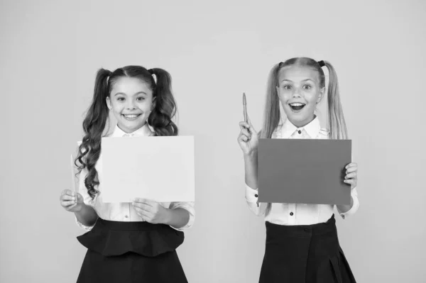 Tengo una idea. Pequeños niños lindos sonriendo de idea genio. Chicas felices sosteniendo hojas de papel para escribir idea sobre fondo amarillo. Niños pequeños con papel vacío para ideas creativas, espacio para copiar —  Fotos de Stock