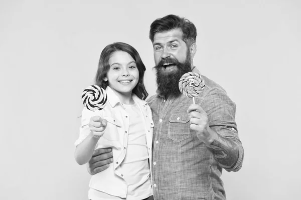 Para ti. Hija y padre comen dulces dulces. El hipster barbudo es un buen padre. papá y niña pequeña niño amor lollipop colorido. vibraciones de verano. feliz descanso familiar. atención médica. Dulce infancia — Foto de Stock