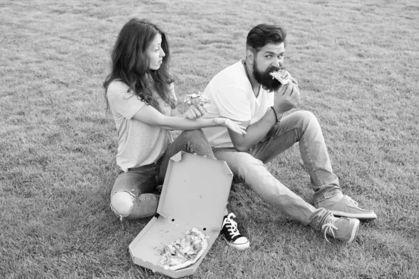 Estudantes famintos a partilhar comida. Puro prazer. Casal comendo pizza relaxante no gramado verde. Entrega de comida rápida. Homem e mulher barbudos gostam de pizza de queijo. Casal apaixonado namoro ao ar livre com pizza — Fotografia de Stock