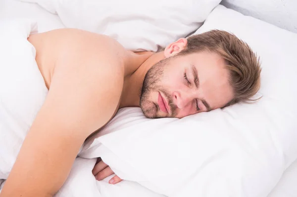 Um homem bonito e sem barba na cama. As dicas dormem melhor. Homem barbudo relaxando na almofada. Travesseiro macio. Durma o suficiente todas as noites. Conceito de saúde. Ritmo circadiano regula ciclo de vigília do sono — Fotografia de Stock