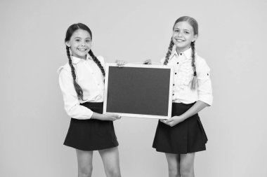 Hazırlandım. Küçük öğrenciler. Küçük kızlar sarı arka planda tahta tutuyorlar. Eğitim için siyah tahtası olan küçük okul çocukları. Küçük çocuklar ders için okul tebeşir tahtası hazırlanıyor, kopya alanı