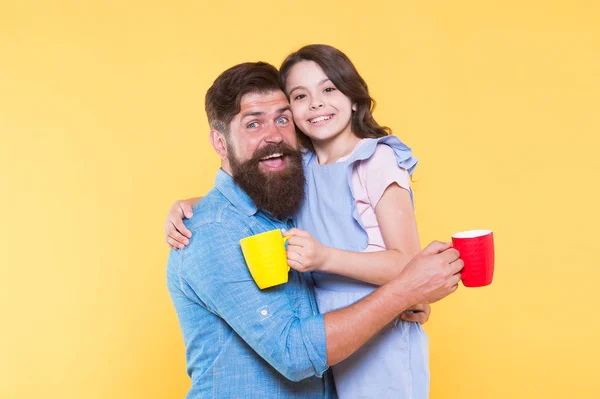 Drink water. Drink fresh juice. Breakfast concept. Good morning. Having coffee together. Lovely family tradition. Drinking tea. Bearded man and happy girl holding mugs. Father and daughter hot drink