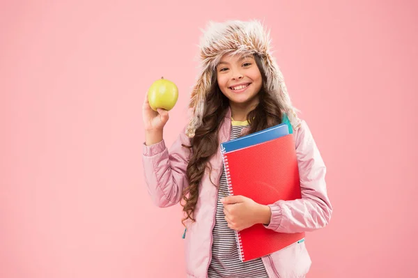 Υγιεινό σνακ. Σύγχρονη εκπαίδευση. Κομψό μαθητριούλα. Κορίτσι μικρή χαμογελαστή μαθήτρια κρατάει μηλόπιτα. Μαθήτρια ευτυχισμένη καθημερινή ζωή. Διακοπές Χριστουγέννων. Χειμερινό εξάμηνο. Έφηβοι με σακίδιο και βιβλία — Φωτογραφία Αρχείου