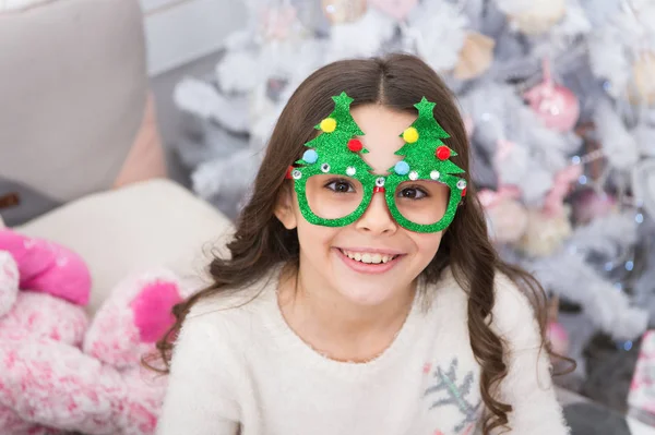 Good vibes. Winter holidays. Small girl at home christmas vacation. Carefree childhood. Kid relaxing. Adorable little girl wear christmas tree glasses photo booth props. Rest and relax. Christmas eve