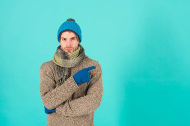 En iyi teklif burada. Tıraşsız yakışıklı adam mavi arka planda kış aksesuarları takıyor. Kış sezonu indirimi. Hippi, kış şapkası eşarbı ve eldiven ördü. Erkek güzeli. Alışveriş konsepti. Kıyafet dükkanı.