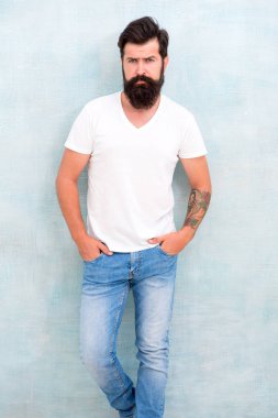 Kişisel stil. Fiziksel çekicilik. Yakışıklı hippi pantolonu. Erkek moda trendleri. Basit ve sıradan bir yaz. Acımasız maço gri arka plan. Erkek şiddeti. Sakallı adam erkeklik saçıyor.