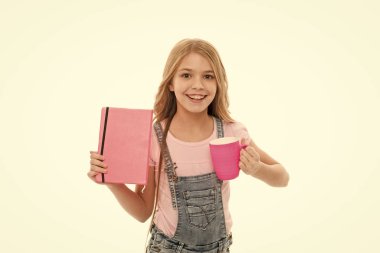 Güne kahvaltı ile başlatın. Sevimli kız tutan fincan ve Not defteri. Küçük çocuk okul kahvaltısının tadını çıkarıyor. Küçük bebek kahvaltı için çay veya süt içiyor. Sabahları kahvaltı yapan mutlu çocuk