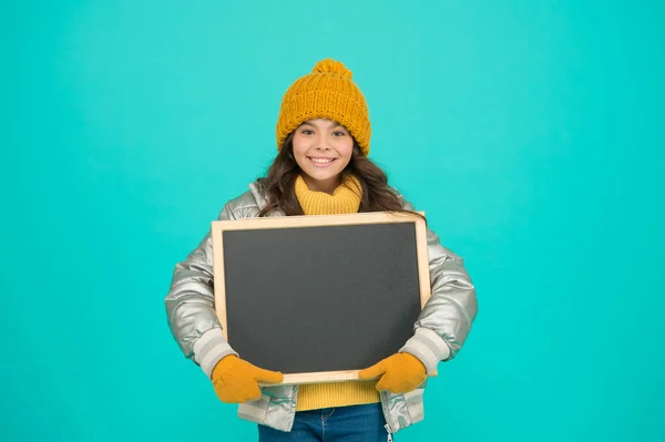 冬のレジャー。寒い季節を通して地域で多くのイベントが開催され、冬の楽しみを全く新しいレベルに取ります。女の子は冬服を着て、空白の黒板のコピースペースを表示します。重要なお知らせ — ストック写真