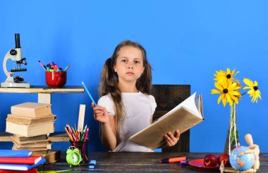 Kız öğrenci masada ciddi yüzle oturur.