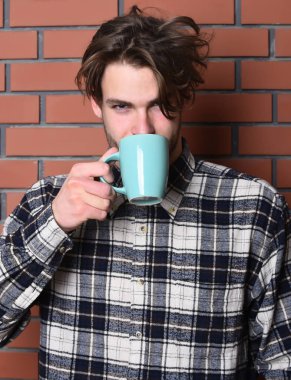 Duvarda fincanı tutan yakışıklı adam.