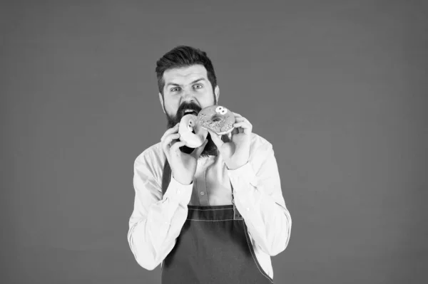 Hipster-bärtige Bäcker essen Donuts. Krapfenbäckerei. bärtiger, gut gepflegter Mann, der Donuts verkauft. Kohlenhydrate und Kalorien. Bäckereibesitzer. Bäckereigeschäft. Backwaren. Süßigkeiten und Kuchen. Junk Food — Stockfoto