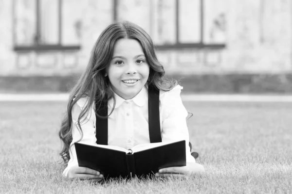 Lesen ist Pass in die Welt. glückliches kleines Mädchen genießt das Lesen von Büchern auf grünem Gras. Kleine Kinder lernen in der Grundschule lesen. Buch ist lesenswert. Schulbibliothek. Wissen und Information — Stockfoto