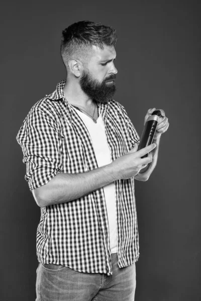 The best shampoo for his hair. Bearded man holding shampoo bottle on grey background. Hipster with beard and mustache choosing shampoo for cleaning hair. Daily strengthening shampoo for men — Stock Photo, Image