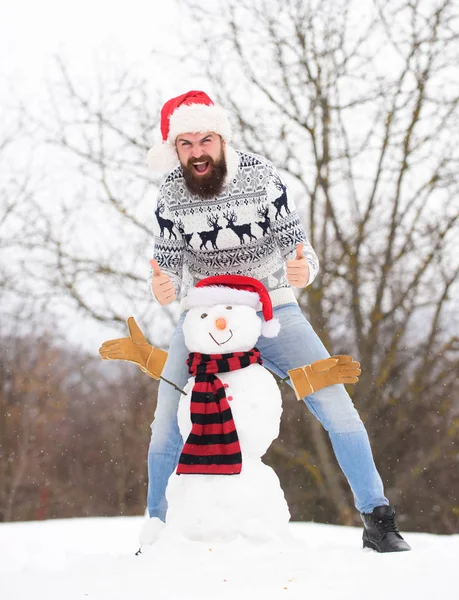 Winter games. Winter activity. Fun and entertainment. Winter vacation. Man made snowman. Hipster with beard outdoors. Man with Santa hat having fun outdoors. Guy happy face snowy nature background — Stock Photo, Image