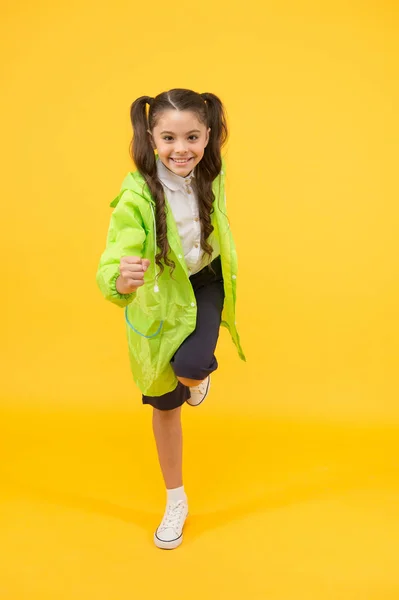 Une écolière porte un imperméable. Imperméables pour enfants avec des formes vibrantes conceptions uniques. Écolière porter des vêtements résistant à l'eau. Jour de pluie. Écolière mignonne se sentent protégés pour le temps du printemps. Concept étanche — Photo