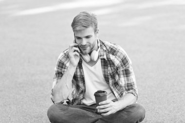 Sabah titreşimleri. adam yere otur. kulaklıkta kaygısız öğrenci. online eğitim. müzik dinleyin. adam damalı gömlek telefonda konuşmak. öğrenci dinlenmek ve şarj. kahve gitmek için. adam kahve içmek