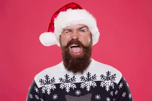 Beste vakantie. knipperende man met baard Kerstman hoed. brutale hipster favoriete trui rode achtergrond. Wintervakantie plezier. Blij gezicht snor. portret van de kerstman met baard. Nieuwjaarsfeest. Kersttijd — Stockfoto