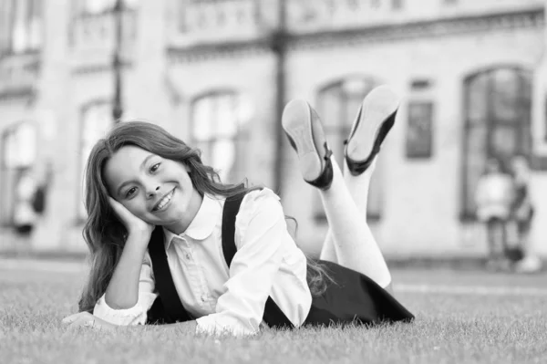 Relájate en el patio del colegio. Buen momento. Vacaciones escolares para descansar. Feliz pupilo sonriente. Niña linda niña que pone hierba verde. Chico feliz relajándose al aire libre. Chica uniforme escolar disfrutar de relajarse. Colegiala alegre — Foto de Stock