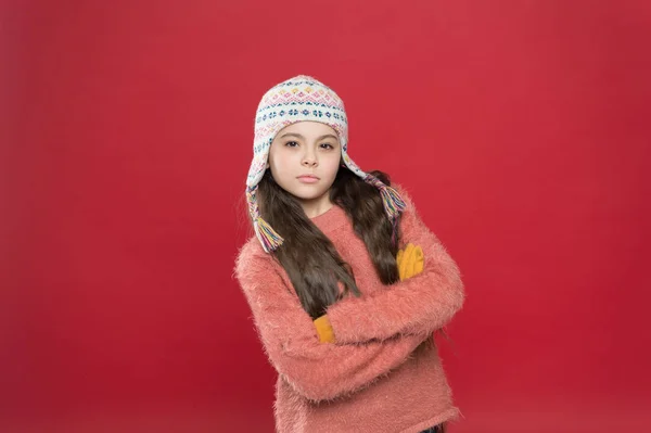 Wintertijd concept. Kleine jongen draagt gebreide hoed. Meisje winter mode accessoire. IJzig weer. Winterkleding. Schattig model genieten van de winter stijl. Klein kind lang haar dragen hoed rode achtergrond — Stockfoto