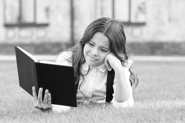 Literatuur voor kinderen. Les over frisse lucht. Schattig klein kinderleesboek buiten. Schoolmeisje schooluniform liggend op het gazon met favoriete boek. Studeren concept. Basisonderwijs. Onderwijsboek — Stockfoto