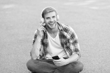 Kolay yoldan öğren. Kulaklık takmış mutlu bir öğrenci. Boş zaman. Online eğitim. Müziği dinle. Kitap konsepti. Erkek kareli gömlek. Öğrenci sakin ol, telefonu kullan. Adam dışarıda sohbet ediyor. Adam yere otur.