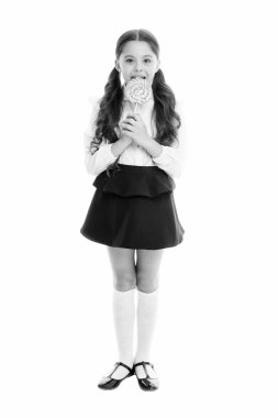 Kendini şekerlerle ödüllendiriyor. Yemek bağımlılığı. Kız tatlı lolipop yiyor. Kız öğrenci üniforması lolipop şeker gibi beyaz arka plan. Sağlıklı beslenme diyeti. Öğrenim için tatlı ödülü