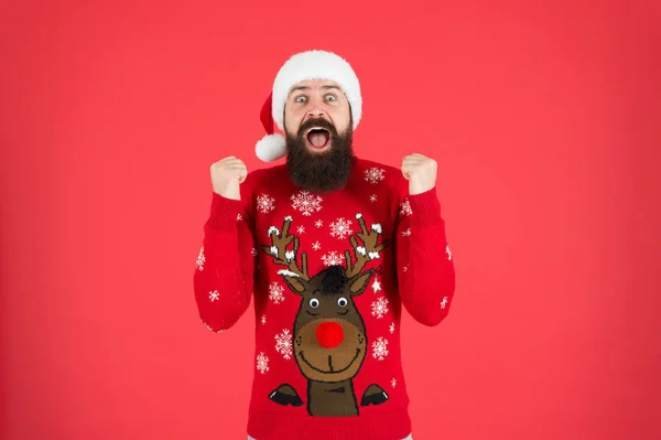 Funny hipster knitted sweater. knitwear fashion. winter holiday celebration. feel joy and hapiness. bearded man santa hat red wall. christmas time. male at xmas party. happy new 2020 year — Stock Photo, Image