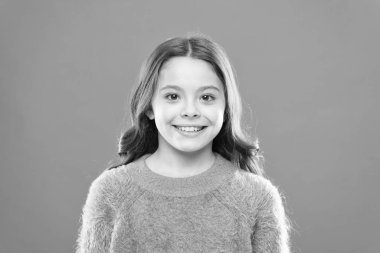 Küçük tatlı kız gülümsüyor. Küçük çocuk sonbahar süveteri. Rahat ol, rahat ol. Neşeli çocuk turuncu arka planı. Tasasız çocukluk. Sağlıklı gülümsemesi. Mutlu çocuklar günü. Keyfin yerinde olsun.