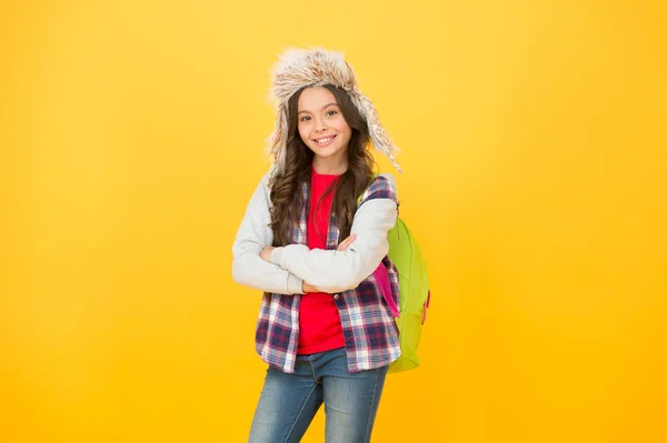 Зимние мероприятия в школе. Маленькая девочка носит шляпу с ушами. зимнее школьное время и каникулы. обратно в школу. рюкзак школьницы желтый фон. Никаких занятий на этой неделе. веселый ребенок ученик — стоковое фото