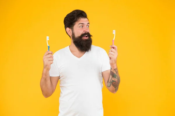 Dentist on board. Happy hipster hold brushes yellow background. Bearded man look at toothbrushes. Dentist and dentistry. Oral health. Dental hygiene. Visit dentist regularly. Dentist needs patience — 图库照片