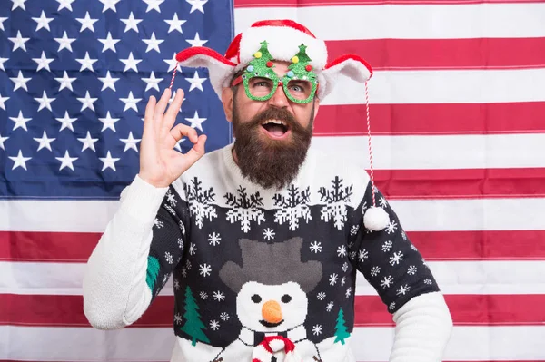 Perfecto. Las tradiciones y las celebraciones navideñas cambiaron mucho con el tiempo. Americano barbudo hipster chico unido alegre celebración. Tradición americana. Santa Claus en bandera americana. Temporada de invierno —  Fotos de Stock