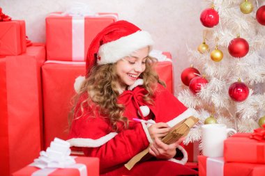 Küçük kız elinde kalem ve kağıt ile Noel ağacı yakınında mektup yazıyor. Çocuk Noel Baba 'ya mektup yazmış. Çocuk Noel Baba kostümü afiyet olsun. Mucizeye inan. Noel Baba 'ya mektup. Dilek listesi