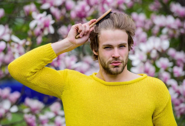 Floral cosmetics concept. Hipster enjoy blossom aroma. Spring beauty. Hairdo styling. Man flowers background defocused. Botany nature. Male beauty. Hair care and beauty. Unshaven man magnolia bloom