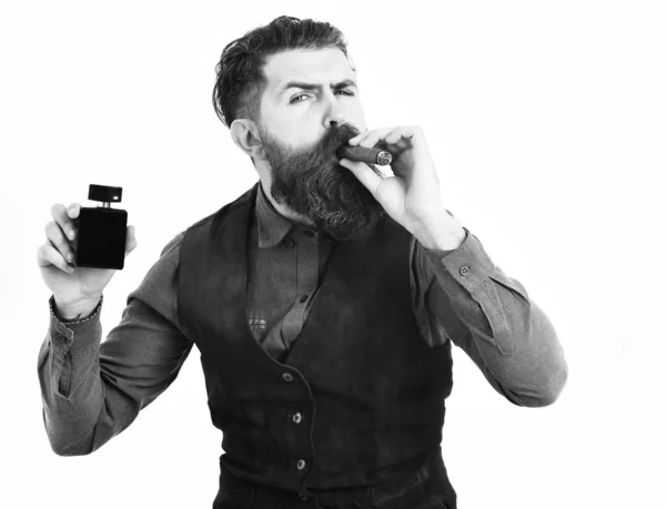 Homme barbu fumant cigare avec un visage sérieux, tenant parfum — Photo