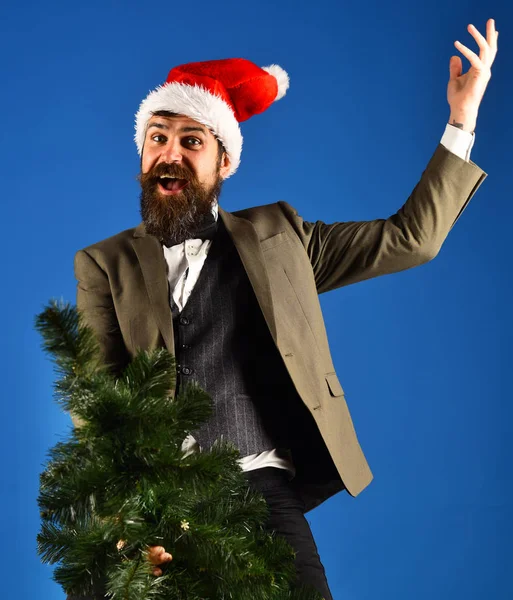 Hombre en sombrero de Santas sentado en la parte superior del árbol de Navidad — Foto de Stock