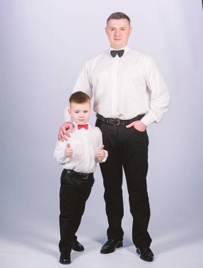 Küçük çocuk ve babası iş adamı. Mavi kan. Aile günü. Babasıyla mutlu bir çocuk. İş toplantısı partisi. Mavi kanlı erkek modası. Ebeveynlik. Babalar günü. Baba ve oğul takım elbise içinde. Smokin stili