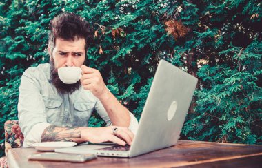 İnternet kafeyi ziyaret etmek. Hipster açık hava kafede çay ve ücretsiz wifi tadını çıkarın. Sakallı adam içki içip kafede internette geziniyor. İnternet erişimi ve taze demlenmiş kahve sağlayan siber kafe