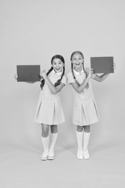 Retro üniformalı mutlu arkadaşlar. Klasik çocuk modası. Okula dönüyorum. Küçük kızlar boş kağıt tutarlar. Çocuklar için ansiklopedi kitabı. Küçük kızlar edebiyatı sever. Eski usul. Duyuru. Boşluğu kopyala.