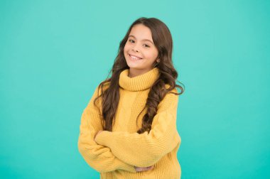 Harika bir saç stili. Pozitif olma kavramı. Duygusal bir bebek. Pozitif çocuk. Hayata olumlu yaklaşım. Pozitif ruh hali. Çocuk psikolojisi. Sevimli gülümseyen kız sarı süveter giyer turkuaz arka plan
