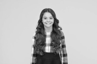 Çocuk rüyasına renk ekliyorum. Sarı arka planda mutlu bir çocuk. Sevimli küçük çocuk resmi okul üniforması giyiyor. Uzun kıvırcık saçlı sevimli küçük kız gülüşü. Çocuk okula geri döndü.