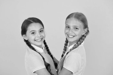 Sarı arka planda mutlu arkadaşlar. Moda güzeli. çocukluk mutluluğu. Kardeşlik kavramı. Eski okul üniformalı küçük kızlar. Klasik tarzda çocuklar. Eski moda. Birlikteyiz.
