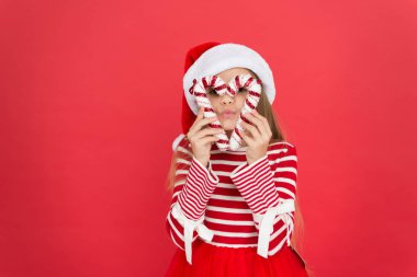 Partide deliriyor. Kırmızı renkli şenlik partisi. Tatlı çocukluk. Küçük kız eğleniyor. Noel Baba Elf çocuk şeker kamışı dekoru. Noel süslemesi. Noel alışverişi zamanı. Mutlu yeni yıl kutlamaları.