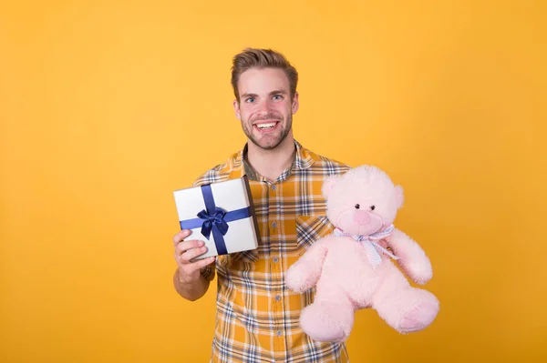 What to buy. happy valentines day. teddy bear plush toy. his favorite holiday. best offer while shopping. macho man teddy bear gift. guy hold present box yellow wall. birthday present surprise — Stock Photo, Image